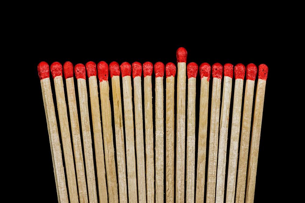 Row of red-tipped matchsticks, with one standing taller than the others.