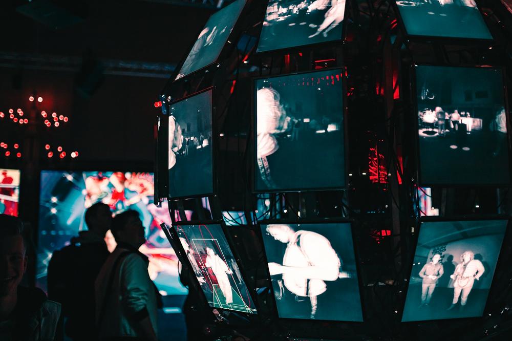 A group of people standing around a display of video screens.
